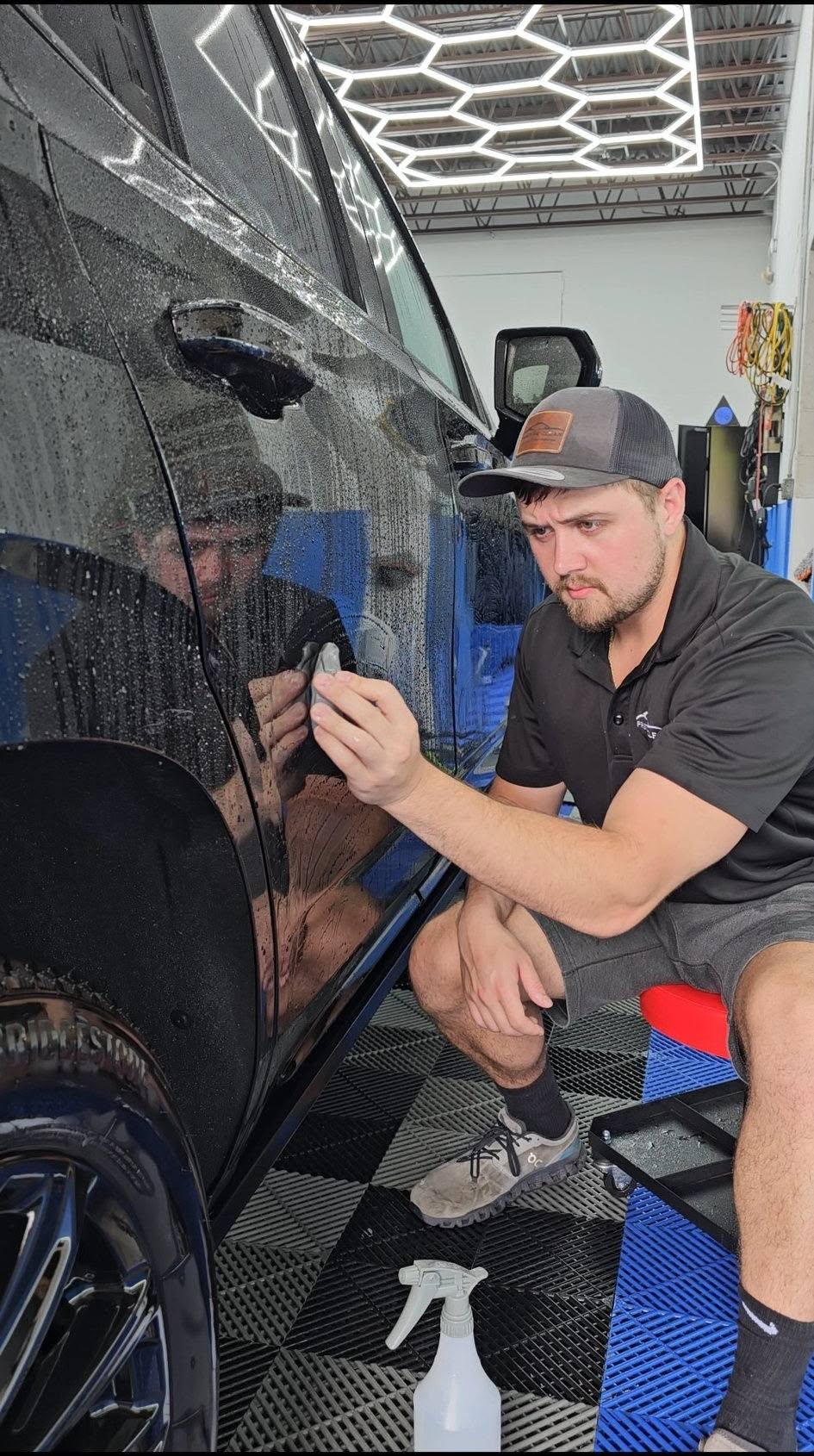 Gerard carefully applying ceramic coating to a black vehicle